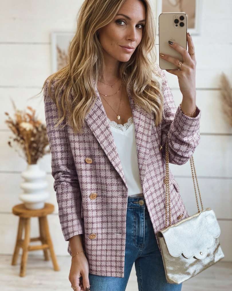 Woman taking a mirror selfie wearing a plaid tweed double breasted blazer and jeans.