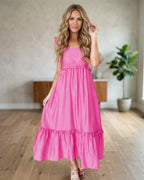 Woman wearing a bonbon pink maxi dress with ruffle sleeves.